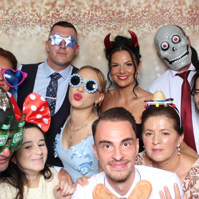 Invitați cu accesorii amuzante în cabina foto, fundal sclipici roz-auriu