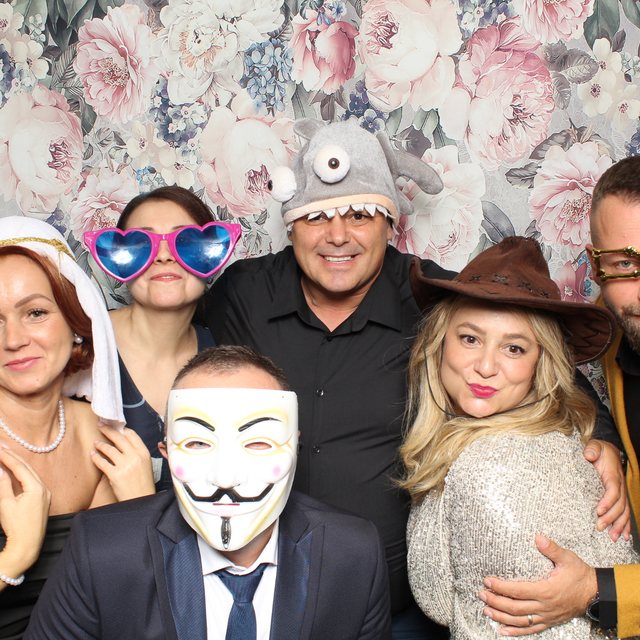 Invitați cu accesorii amuzante în cabina foto, fundal tapet floral roz